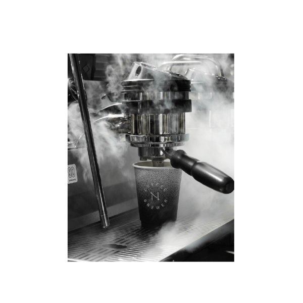 An espresso machine pulling a shot into a NODI cup, in black and white
